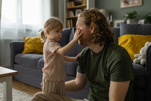 Little daughter consoling his sad father at home.