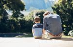 Father sitting and comforting sad son with autism, mental disorder and depression on garden step backyard patio. Back view of caring, loving and kind single parent supporting, comforting and talking